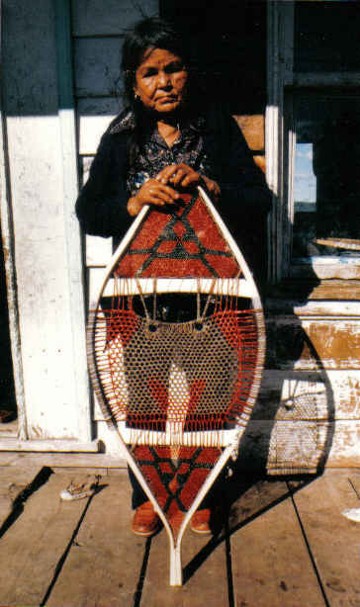 Elisabeth Flamand with the finished snowshoe painted with traditional powdered pigments ; the end sections are painted solid red and the midsection is outlined in red according to a traditional pattern . The powdered pigment is applied to the wet snowshoe weave to allow for better penetration ;Manouane, Quebec , 1983 ; from ''Making the Attikamek Snowshoe'', photo , Henri Vaillancourt