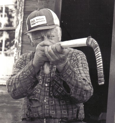 Jocko Carle sighting along the bow piece of a new birchbark canoe . The bow profiles of Algonquin birchbark canoes vary somewhat  according to the taste and whim of the individual builders ; from ''Building an Algonquin Birchbark Canoe '' ; photo  Henri Vaillancourt ; Maniwaki Quebec 1980