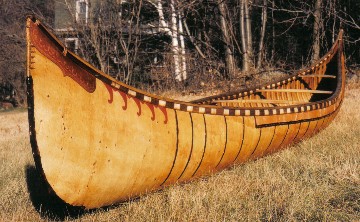 A common size tumblehome sided Malecite birchbark canoe of the old -form high ended style. The deck piece,made of ''winter bark'', is decorated with etched  double curve designs .